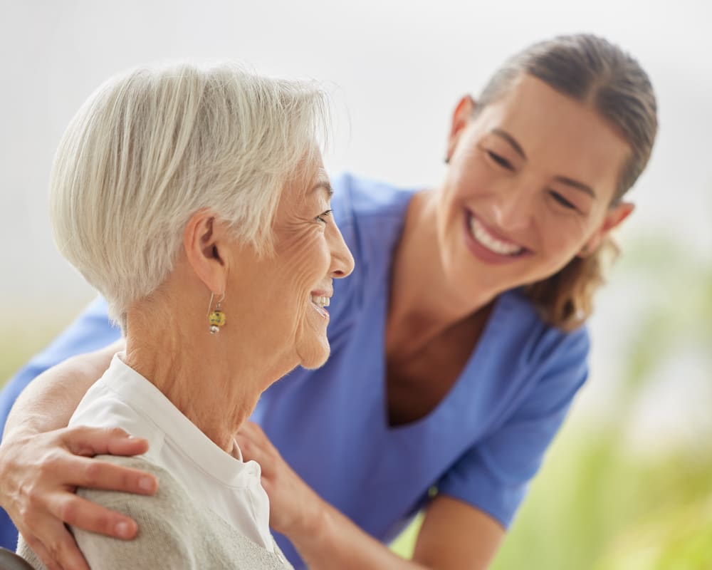 A senior lady is smiling while talking to her dental assistant.