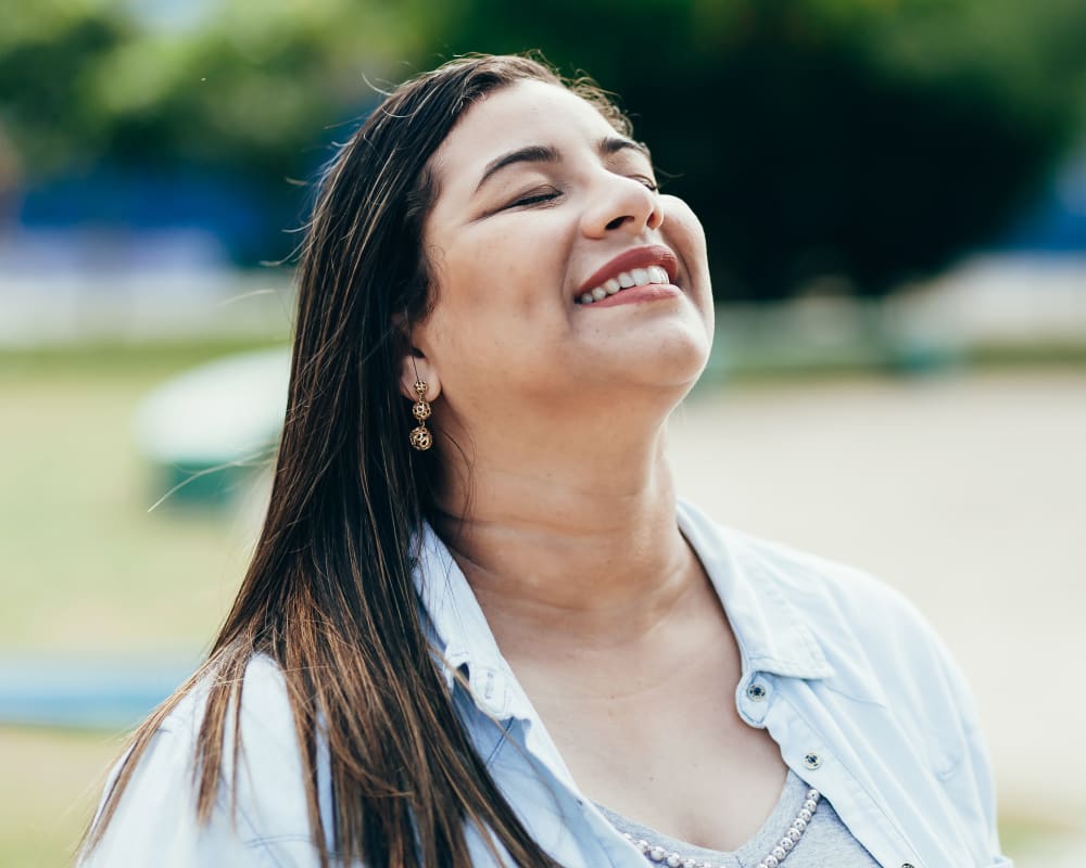 A woman tilts her head up with her eyes closed, absorbing the sunlight.