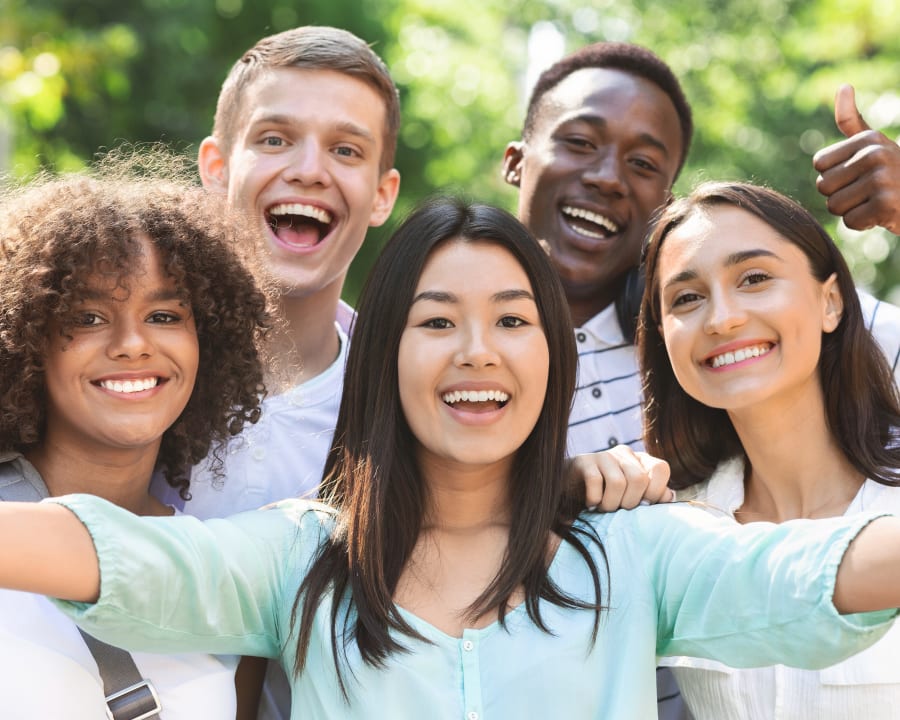 A diverse group of teenagers smile for the camera, showing off bright white teeth that are straight.